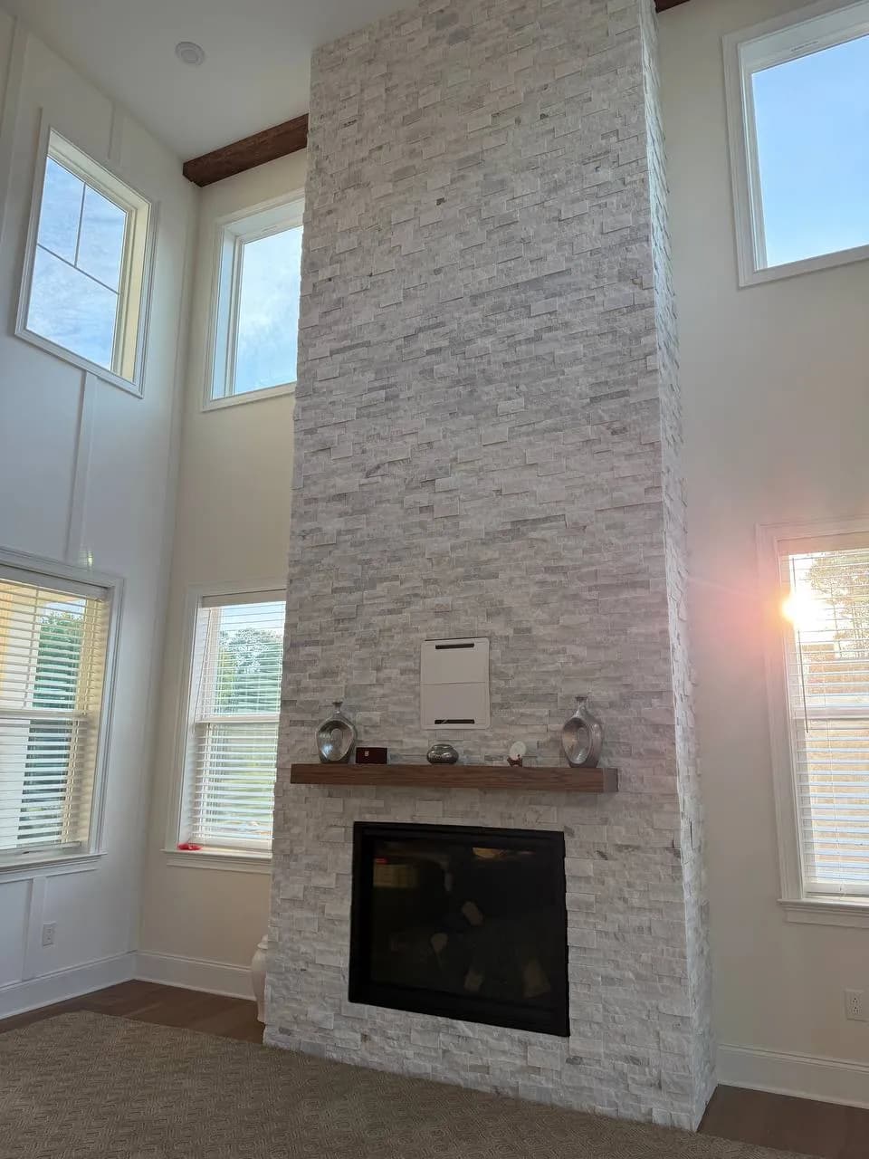 Split-face marble fireplace wall rising past the second-story windows, seen from the side in morning light