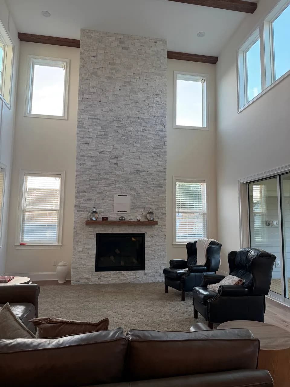 Floor-to-ceiling white split-face marble fireplace wall in a two-story great room